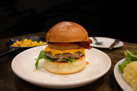 hawaiian burger on white plate on wooden table over black background in restaurantの写真素材