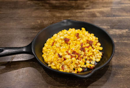 sweet buttered corn with ham in rustic pan on wooden tableの写真素材