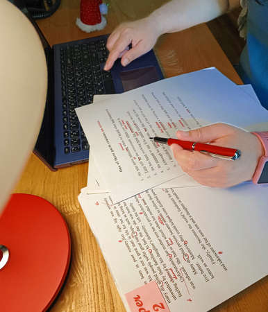 paperwork for proofreading on wooden table with lamp and laptop