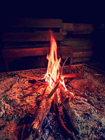 red bonfire in sandbox by wooden bench in countrysideの写真素材