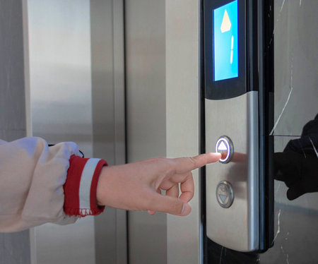 hand pressing on elevator button with light on in hotelの写真素材