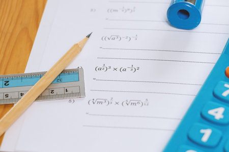 math problems worksheet with stationery on desk in classroomの写真素材