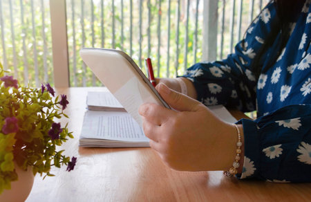 hand holding red pen over blurred paperwork on wooden table in office for proofreading concept