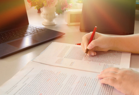 hand holding pen over blurred proofreading paper on table in office