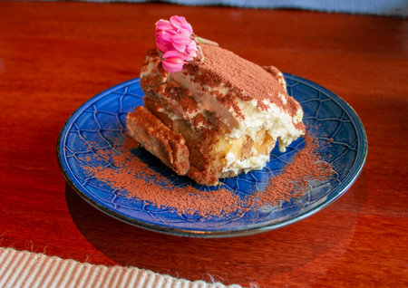 tiramisu cake with cocoa powder and pink flower on topの写真素材