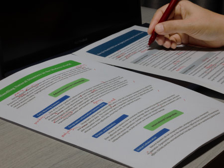 proofreading paperwork on table with computer laptop and penの写真素材