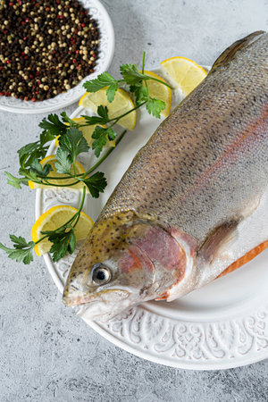 Whole salmon with lemon and spices on paper on a white marble backgroundの写真素材