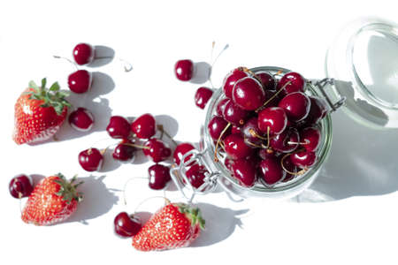 Top view of strawberries and cherries on a white background in a glass jarの写真素材