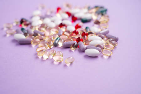 Vitamins and tablets in bulk on a pink background