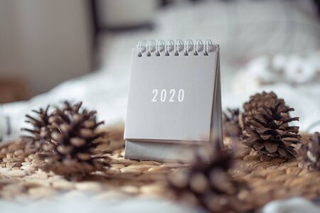 New Year 2020 grey calendar with lights on rustic server with cones and wooden Christmas tree toys