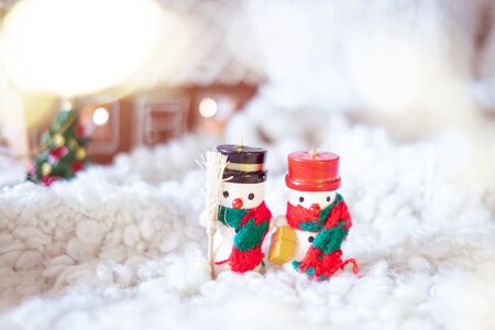 Little wooden snowmen and gingerbread house with lights. Christmas decorations