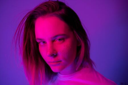 Young girl portrait in neon pink and violet lights with glitter freckles on face. Clubber, night life concept. Copy space.の写真素材