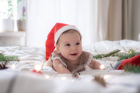 little cute baby girl portreit in red christmas santa hat with lightsの写真素材