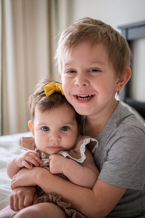 little infant baby girl sitting together with her toddler brotherの写真素材