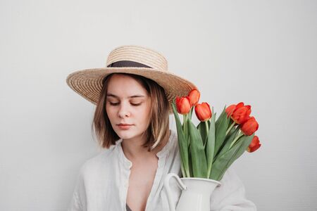 young woman in hat with red tulip bouquetの写真素材