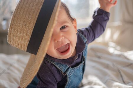 Little infant girl in straw hat smiling and laughing. Family lifestyle.の写真素材