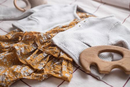 Mustard baby romper with knitted sweater and accessories with wooden toy and sunglasses.の写真素材