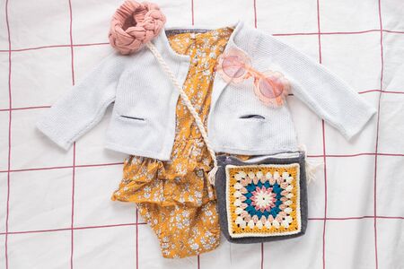 Mustard baby romper with knitted sweater and accessories with wooden toy and sunglasses
