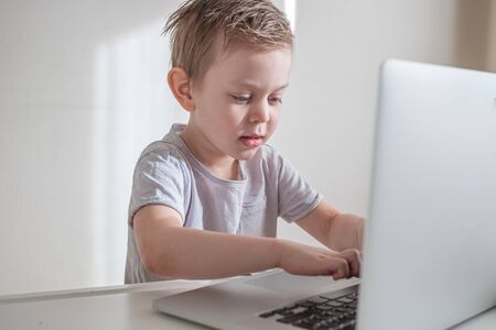 Preschooler boy learning through laptop online. Distance education concept. Home isolation