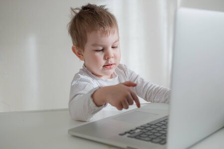 Toddler boy working, learning trough laptop online. distance education concept. Home isolation quarantineの写真素材
