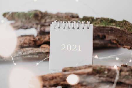 New Year 2021 grey calendar with lights in rustic natural style with tree barkの写真素材