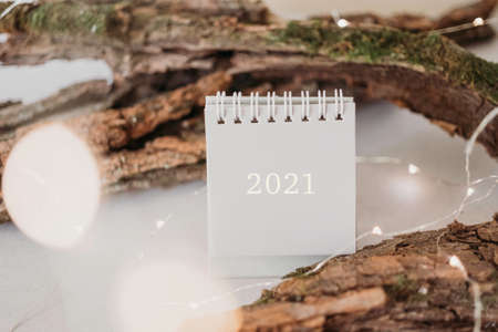 New Year 2021 grey calendar with lights in rustic natural style with tree barkの写真素材