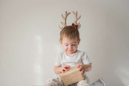 Little infant girl with shiny glitter rain deer horns costume. New year and christmas party celebration. Christmas holidays.の写真素材