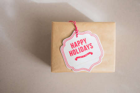 New Year Christmas present in craft paper on neutral natural backgroung with lights in rustic styleの写真素材