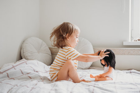 Toddler girl playing with her doll at homeの写真素材