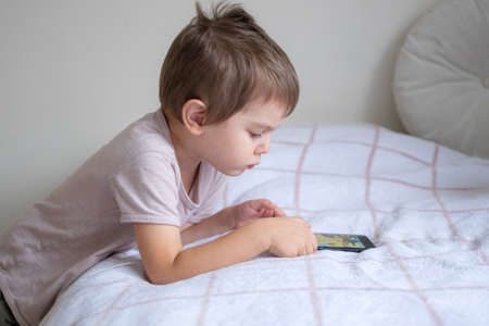 Little preschool boy playing via smartphone at homeの写真素材