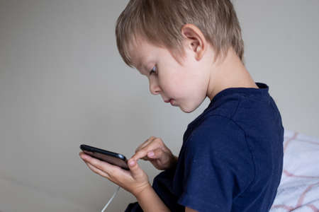 Little preschool boy playing via smartphone at homeの写真素材