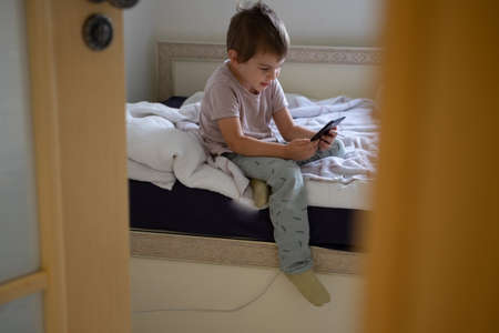 Little preschool boy playing via smartphone at homeの写真素材