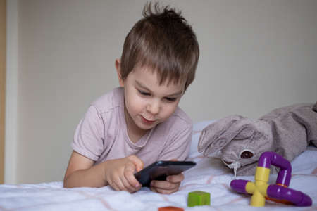 Little preschool boy playing via smartphone at homeの写真素材