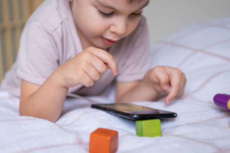 Little preschool boy playing via smartphone at homeの写真素材