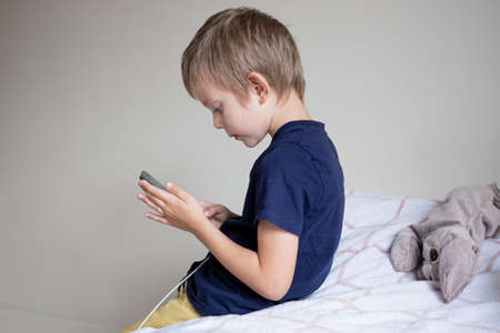 Little preschool boy playing via smartphone at homeの写真素材