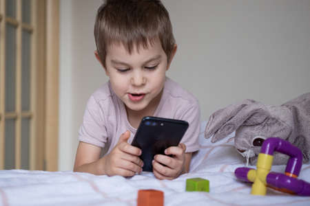 Little preschool boy playing via smartphone at homeの写真素材