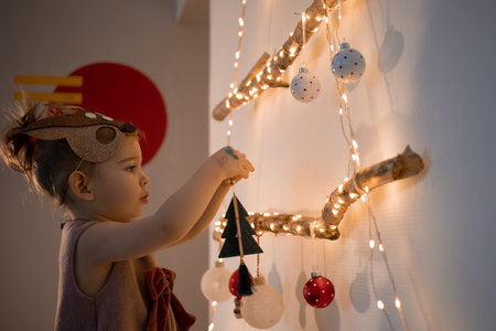 Toddler girl decorating christmas tree at home. Eco friendly alternative Christmas treeの写真素材