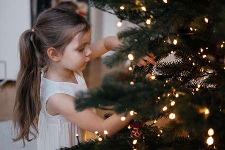 Toddler girl decorating christmas tree at homeの写真素材