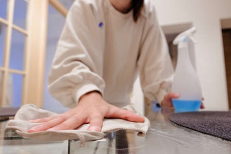 Young woman cleaning a table at home. Doing chores. Housekeeping. Spring clening