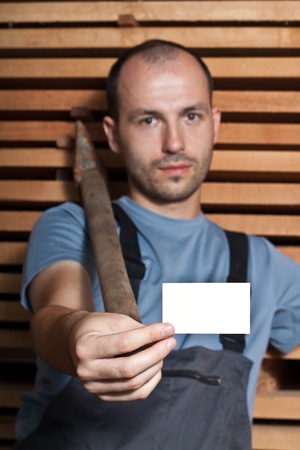 Craftsman with a big hammer holding a business card on wooden backgroundの写真素材