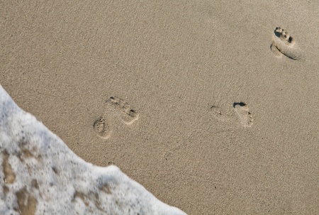 Three footsteps on the beach coming out of the water.の写真素材