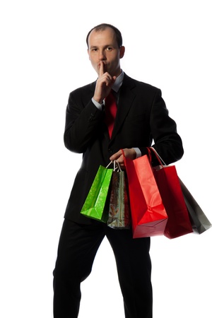 Businessman with shopping bags and making quiet sign with hand, vertical shot isolated on white.の写真素材