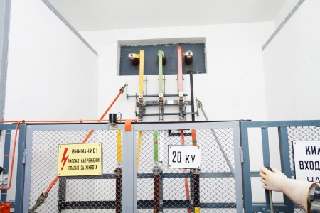 High voltage equipement with a fence, warning signs and hand of a worker in protection gloveの写真素材