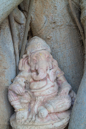 Statue Hindu God Ganesha sitting in the root of treeの写真素材