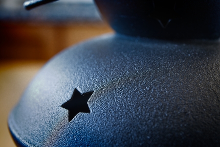 Black metal lampholder with carved stars on a wooden tableの写真素材