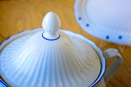 White porcelain tureen with patterned flowers on a wooden tableの写真素材