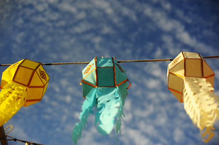 Colorful paper lanterns hanging on a rope with blue sky backgroundの写真素材