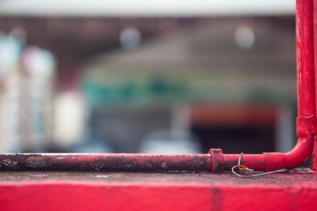 Red metal pipe on the roof in the city, blurred background.