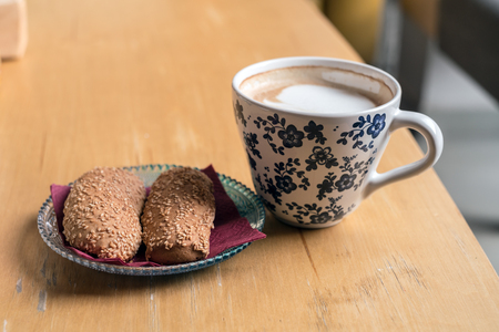 Cup of Hot Coffee with bread cookies served on wooden table