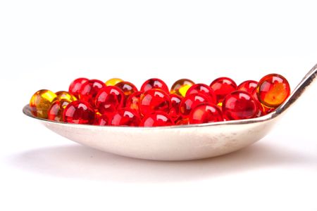 Spoon with red and yellow capsules isolated on whiteの写真素材